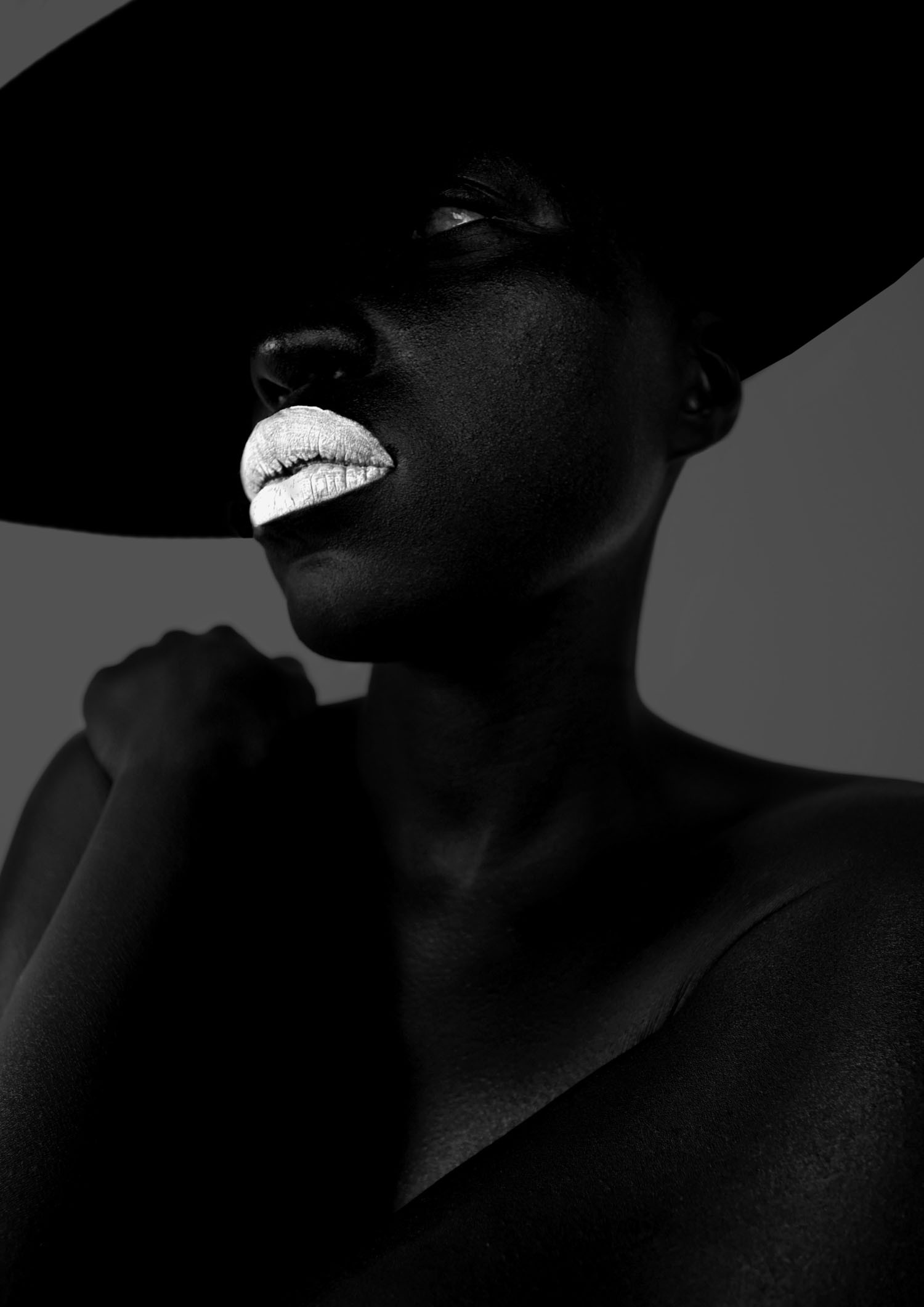 Dark beauty portrait with a wide-brim hat and metallic lips