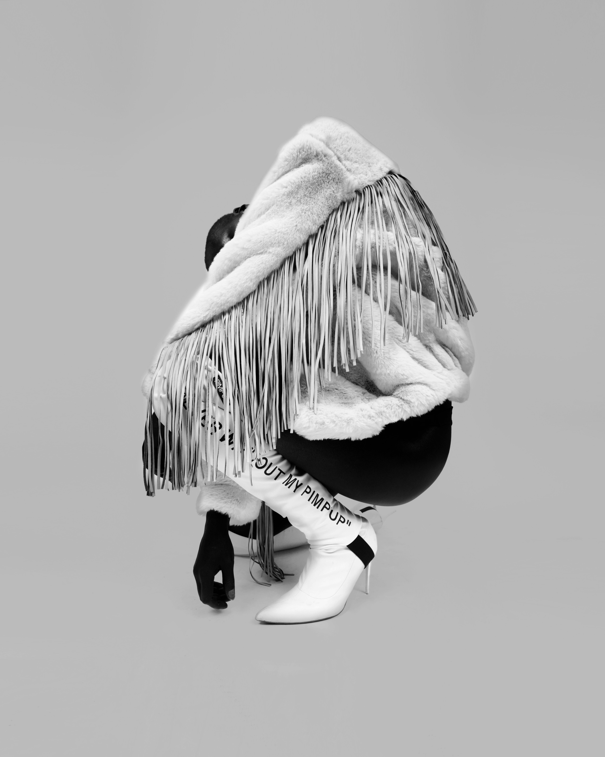 Sculptural monochrome portrait in a fringed white coat